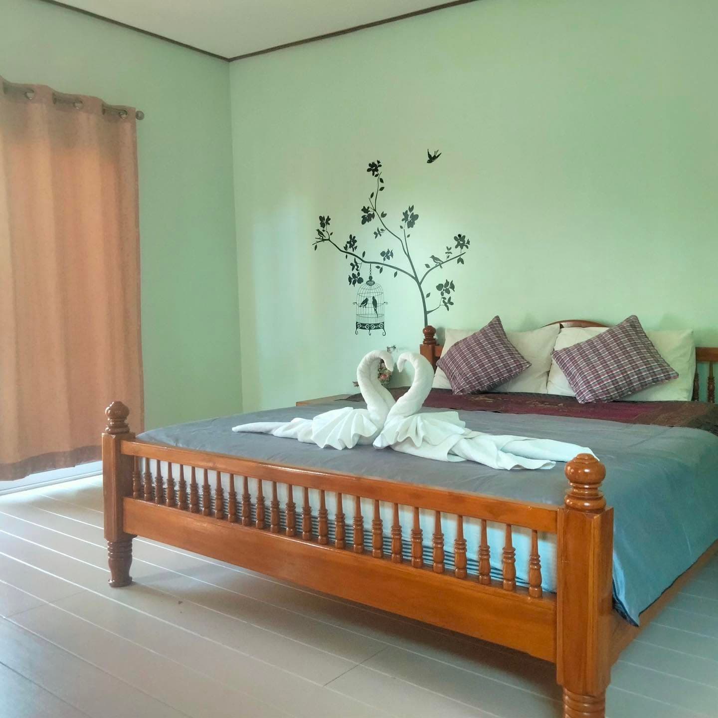 ห้องเตียงใหญ่ผนังสีเขียวอ่อนในอาคารพิชา